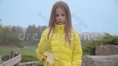 <strong>一</strong>个穿着黄色外套的<strong>可爱</strong>白人女孩站在秋天公园的肖像。 带着<strong>一堆</strong>黄叶的漂亮孩子